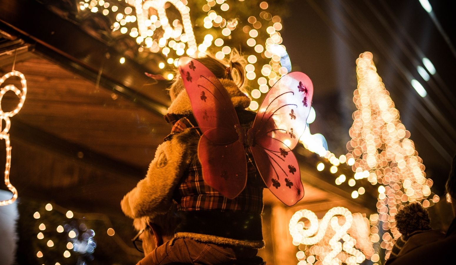 Puestos de madera iluminados y una gran noria en los mercadillos navideños de Flandes, ideal para visitar en familia durante el Puente de Diciembre.